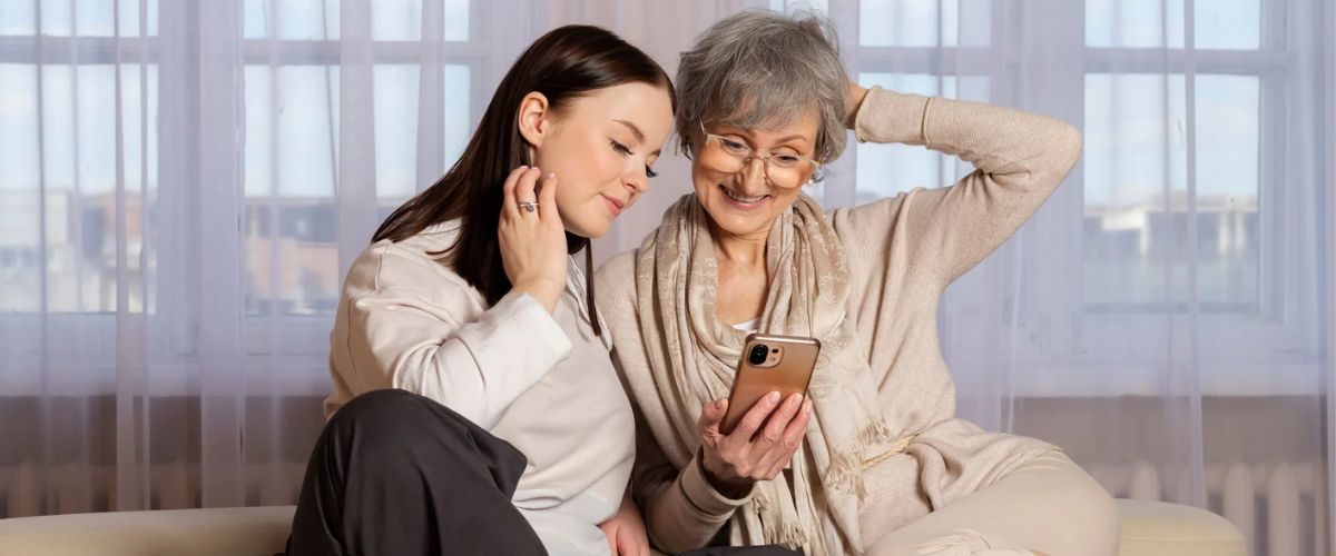 Mother and daughter sitting together looking at a smartphone on Mother’s Day