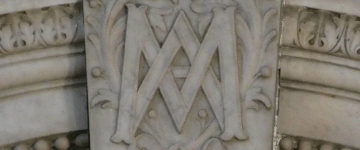 Marble carving of the Marian monogram “M” with decorative floral scrollwork