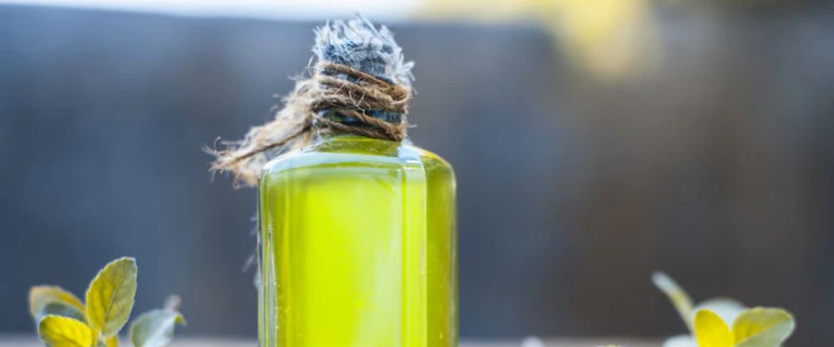 Bright green oil in a small glass bottle with a twine-wrapped cap, symbolizing oil for Christ’s burial, surrounded by leaves and herbs
