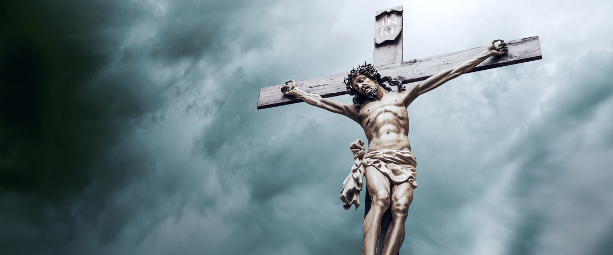 Statue of Jesus Christ crucified on a cross under a cloudy sky