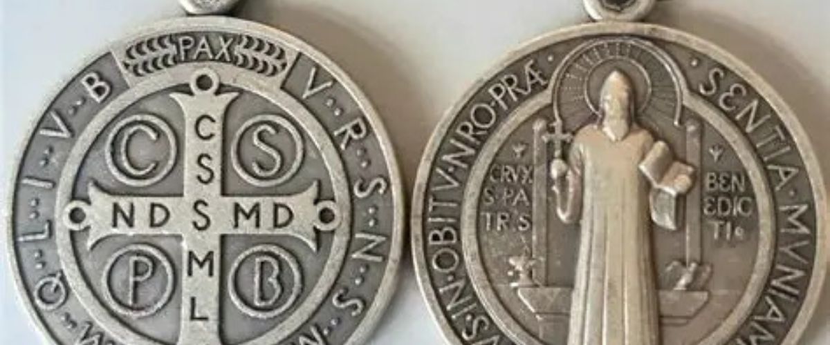 St. Benedict medal with engraved saint image and Latin inscriptions on both sides.