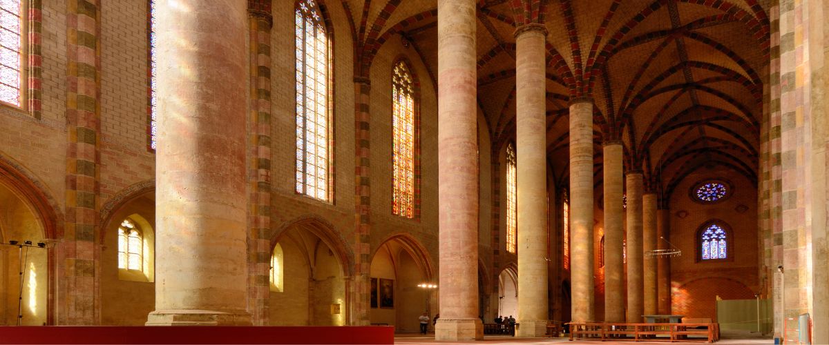 Interior of a grand church with tall columns and stained glass windows, associated with St. Thomas Aquinas