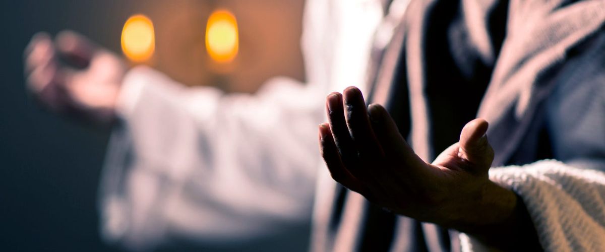 Outstretched hands in prayer with candlelight, symbolizing worship in the Upper Room