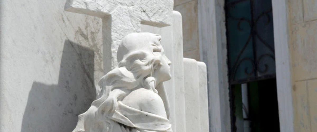 White stone statue beside a large cross outside a church