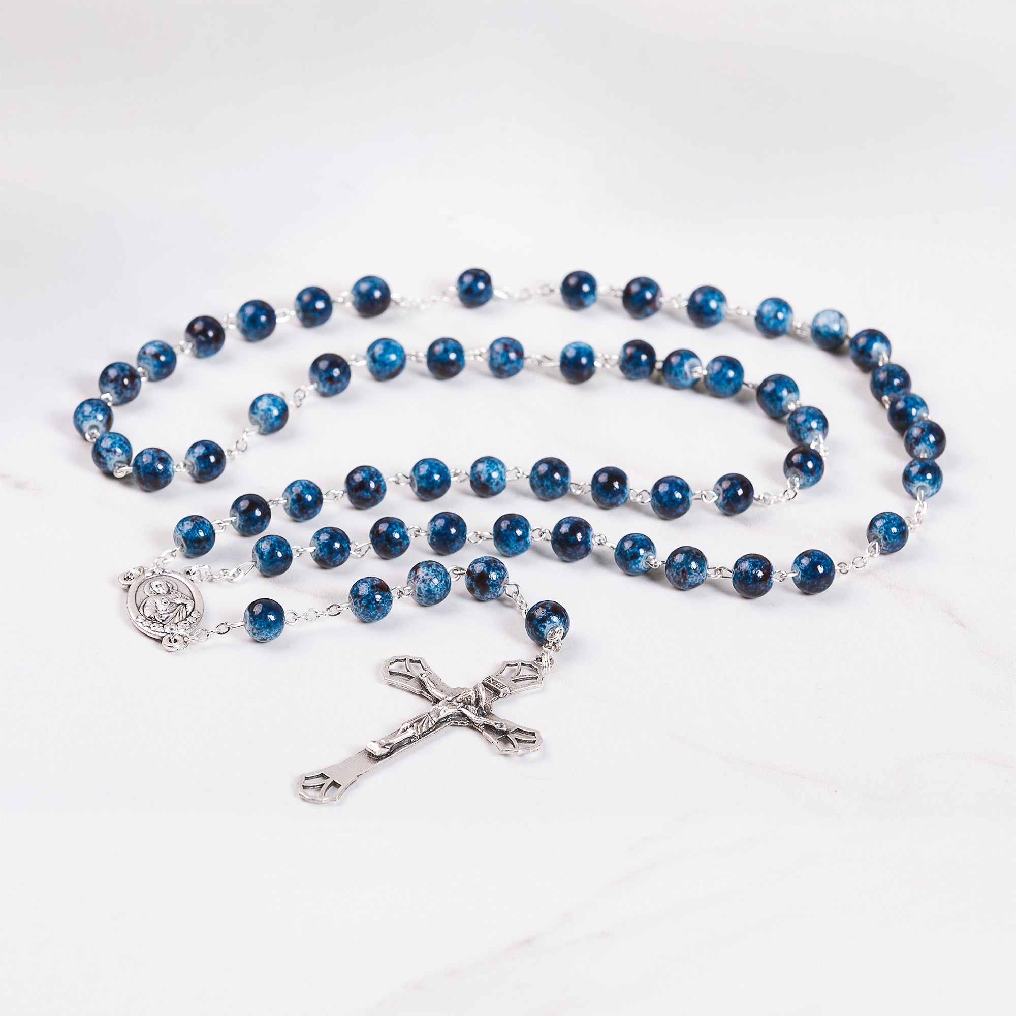 Catholic rosary with round blue beads, silver chain, and crucifix charm.