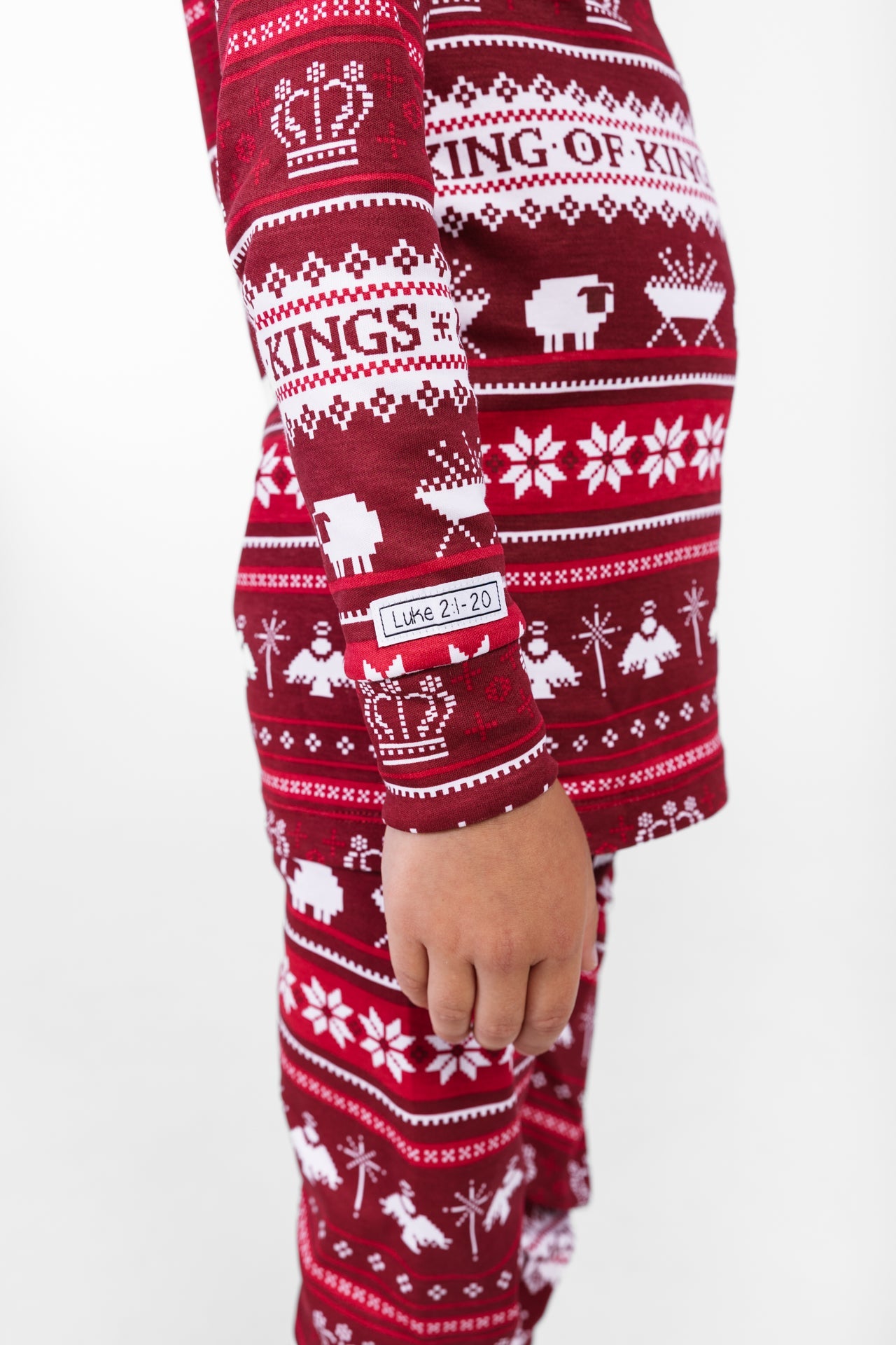 Matching Pajamas, red and white with a "King of Kings" pattern and the tag "Luke 2:1-20" at the wrist.