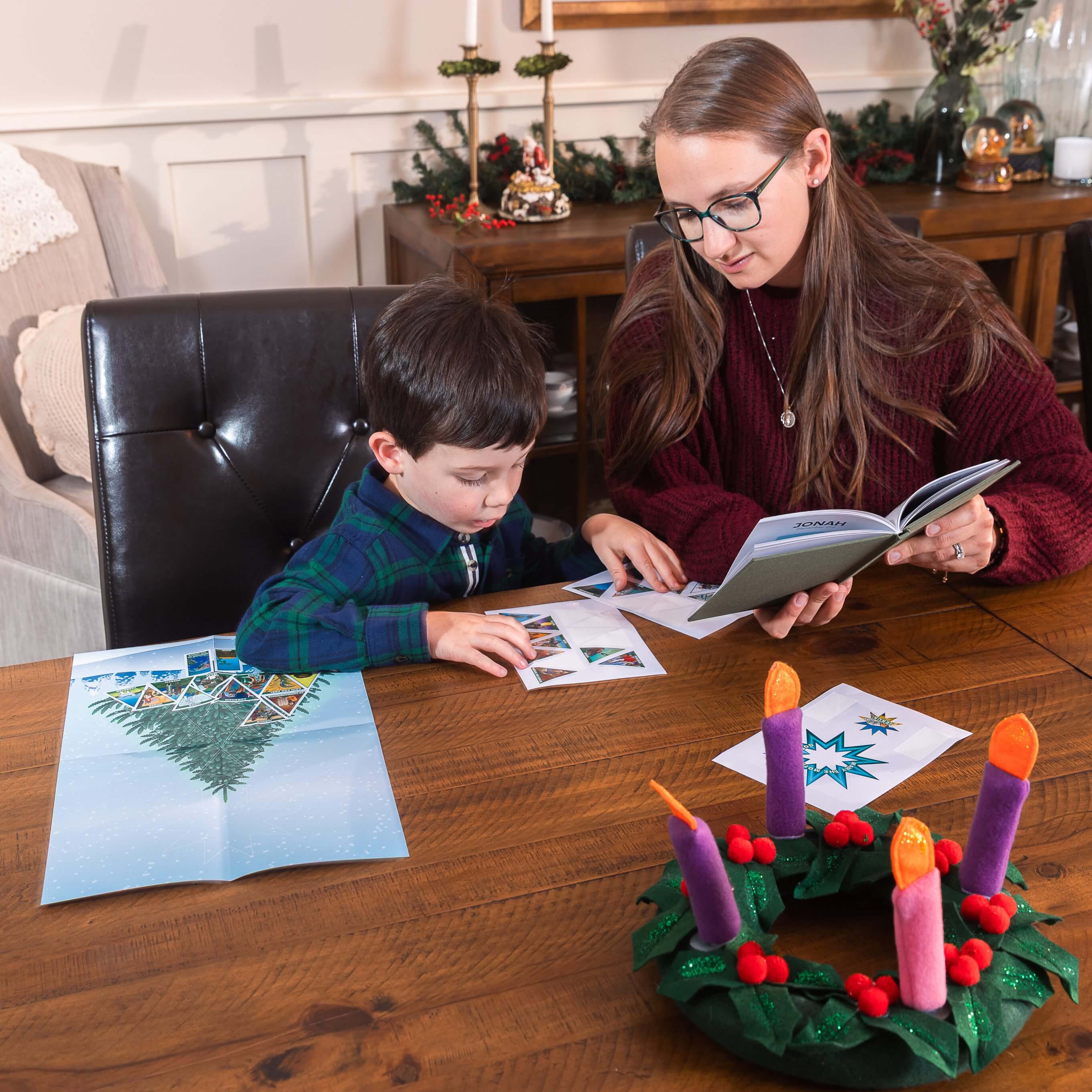Woman and child sitting at a table with Christmas decorations, including an advent wreath.