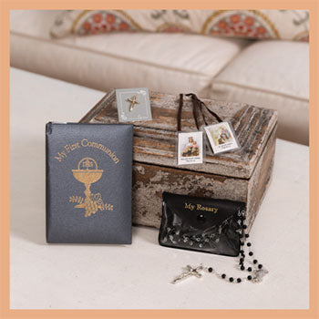Collection of religious items including a book, rosary, and wooden box on a couch.