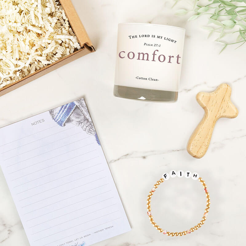 Candle, bracelet, and stationery items on a marble surface