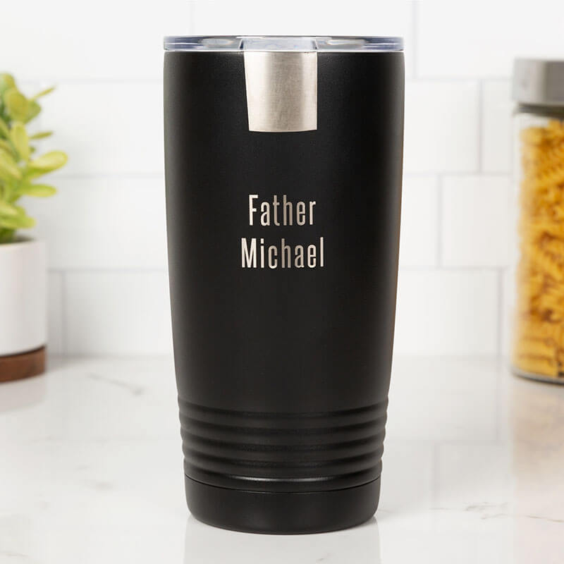 Black insulated tumbler with 'Father Michael' engraving on a white surface.