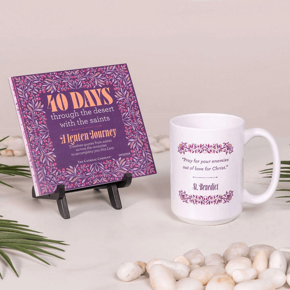 Purple book titled '40 Days through the desert with the saints' and a white mug with text on a light surface.