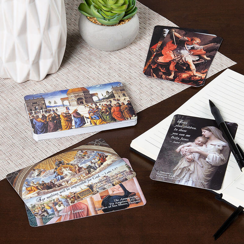 Set of prayer cards on a table with a plant and notebook.