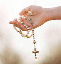 Hand holding a rosary with a blurred background