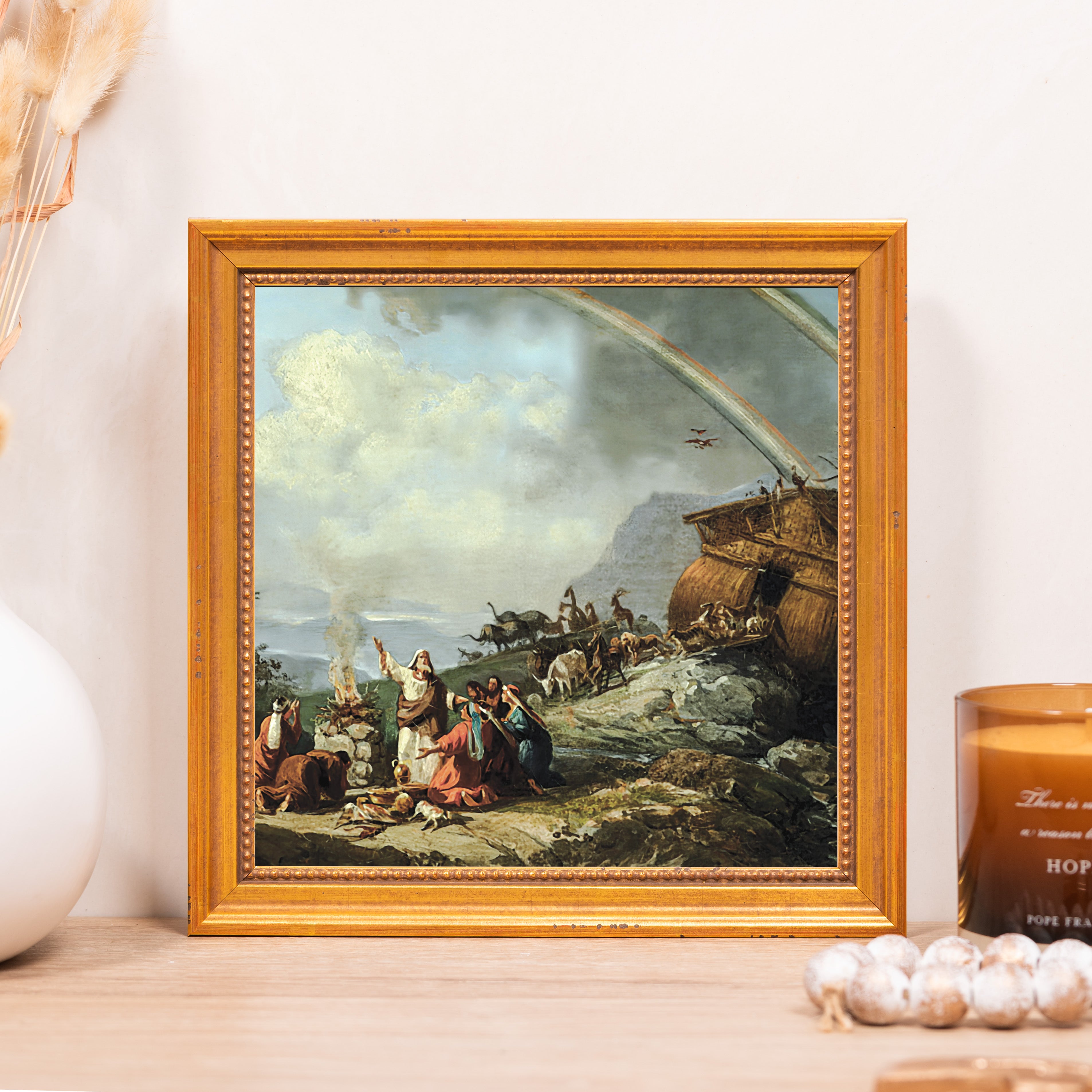 Framed painting of Noah's Ark in a gold frame depicting humans and animals exiting the ark after the flood, with a rainbow in the sky.