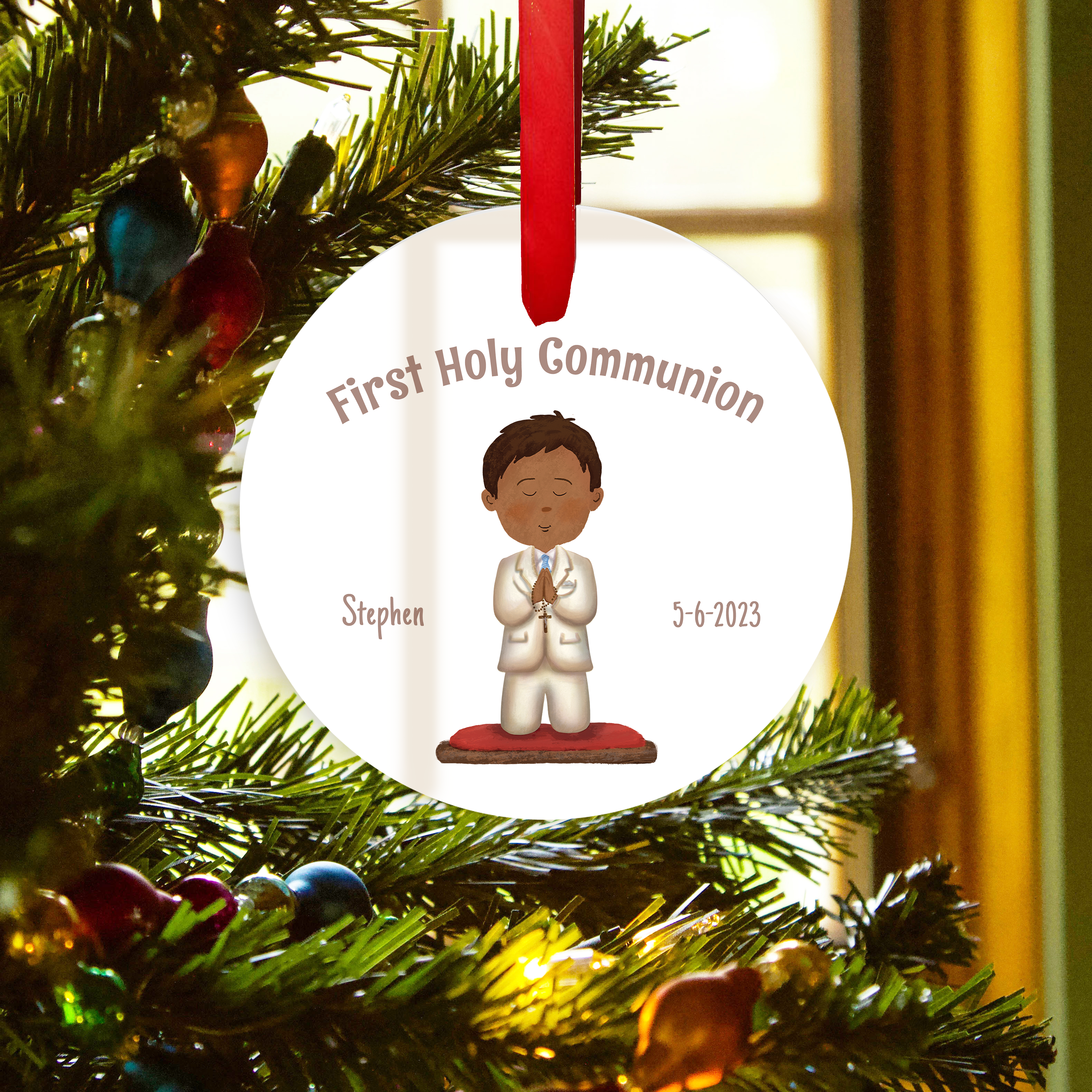 Round, White ornament for First Holy Communion with image of boy wearing white suit and red ribbon on tree.
