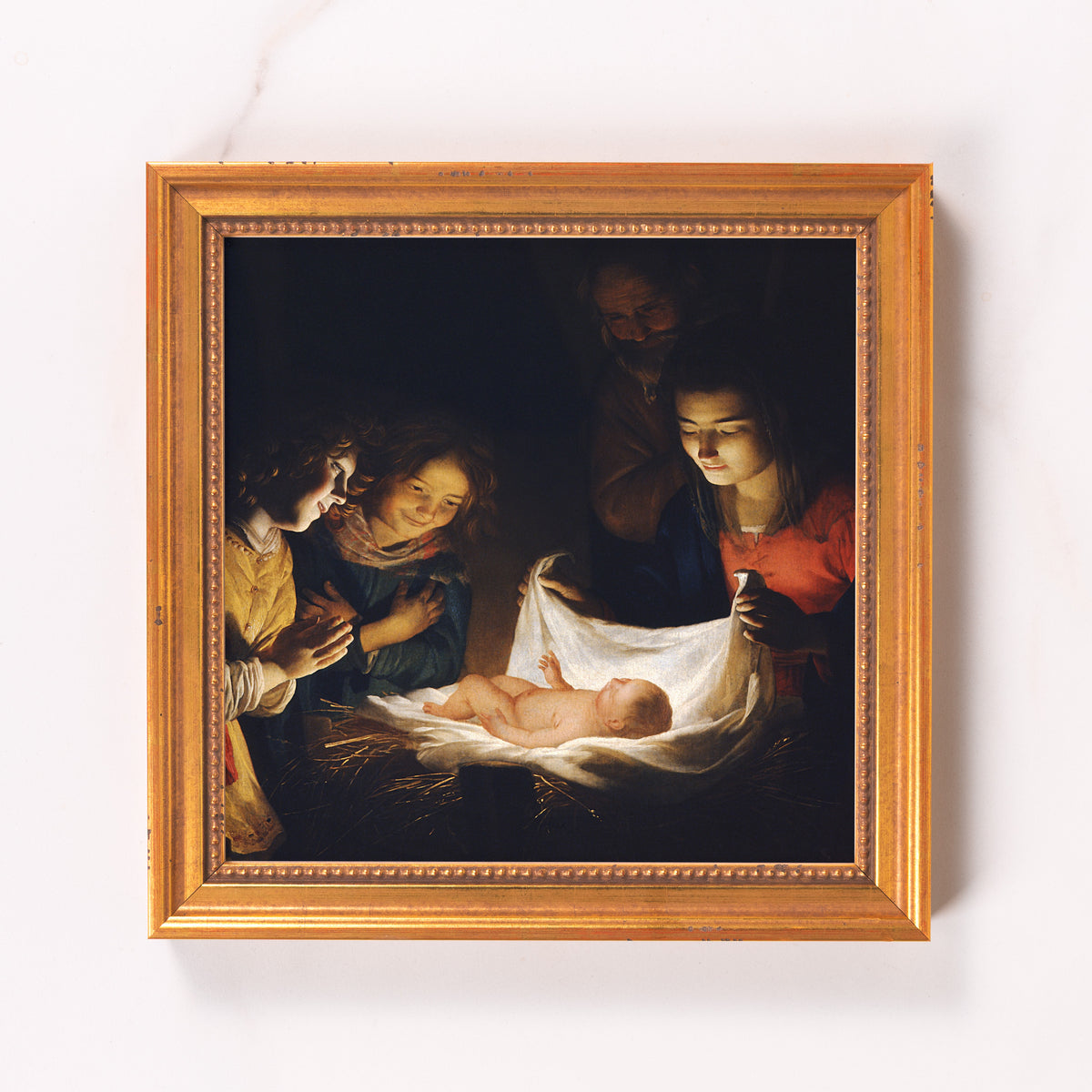 Framed art print of the Nativity scene with golden frame and dark background.