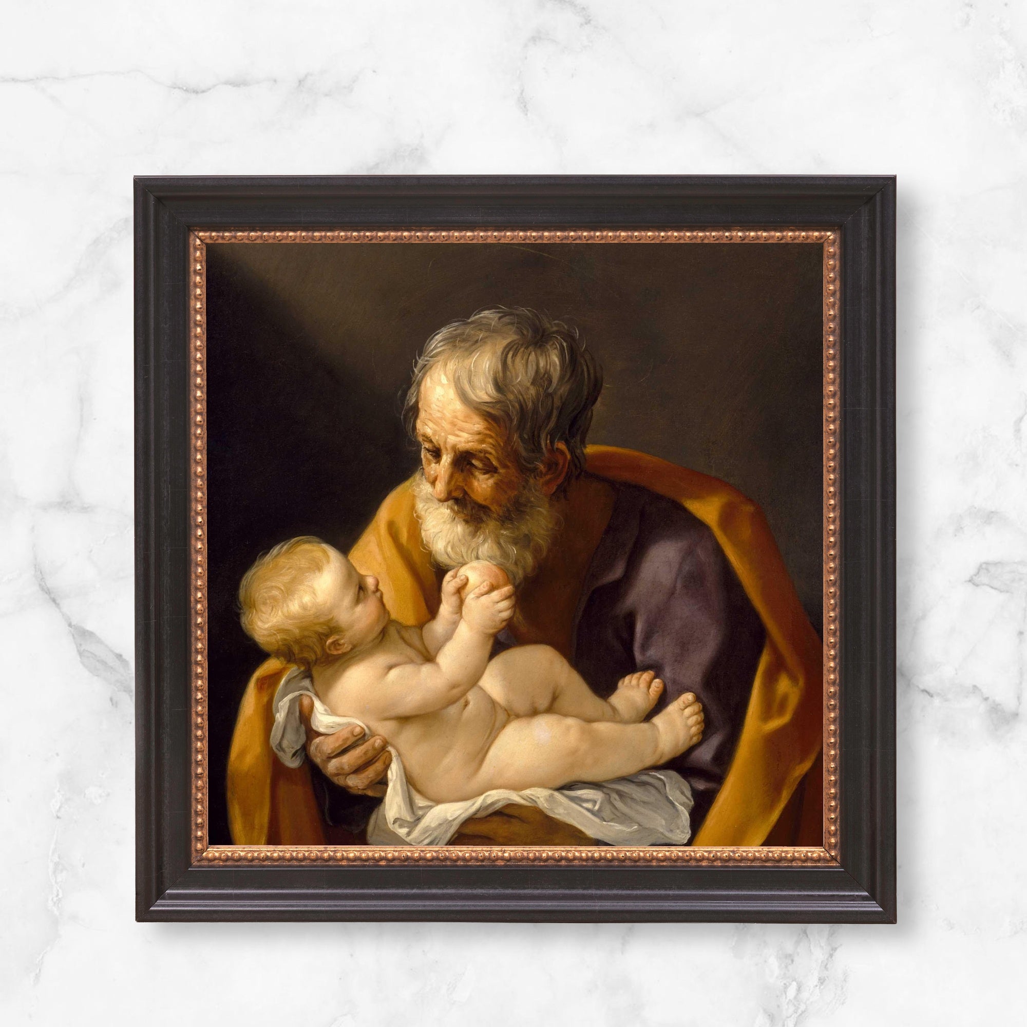 Framed art print of Saint Joseph and the Christ Child in dark wood frame with gold inner trim.