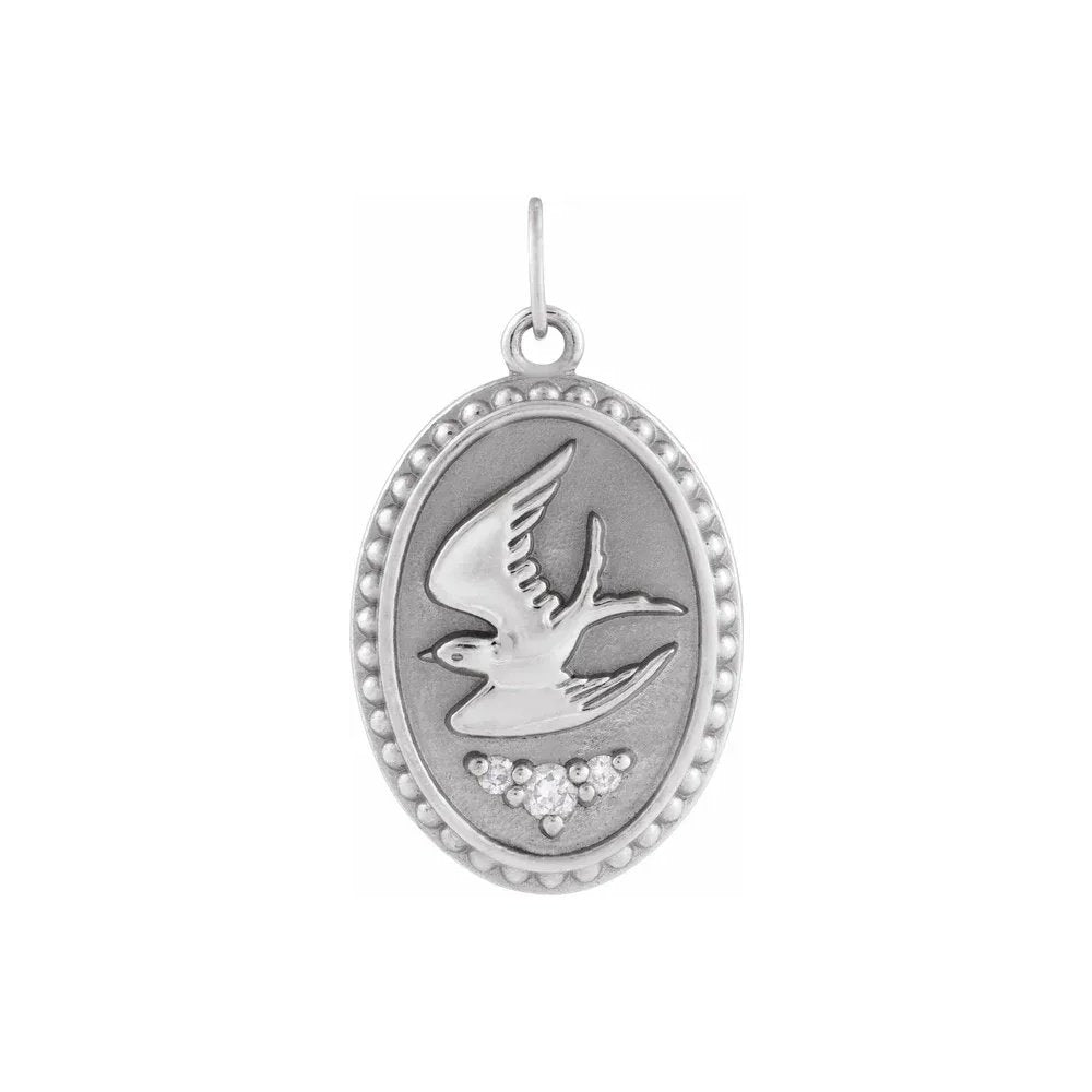 Silver pendant showing a bird in flight, with small gems, in an oval design.