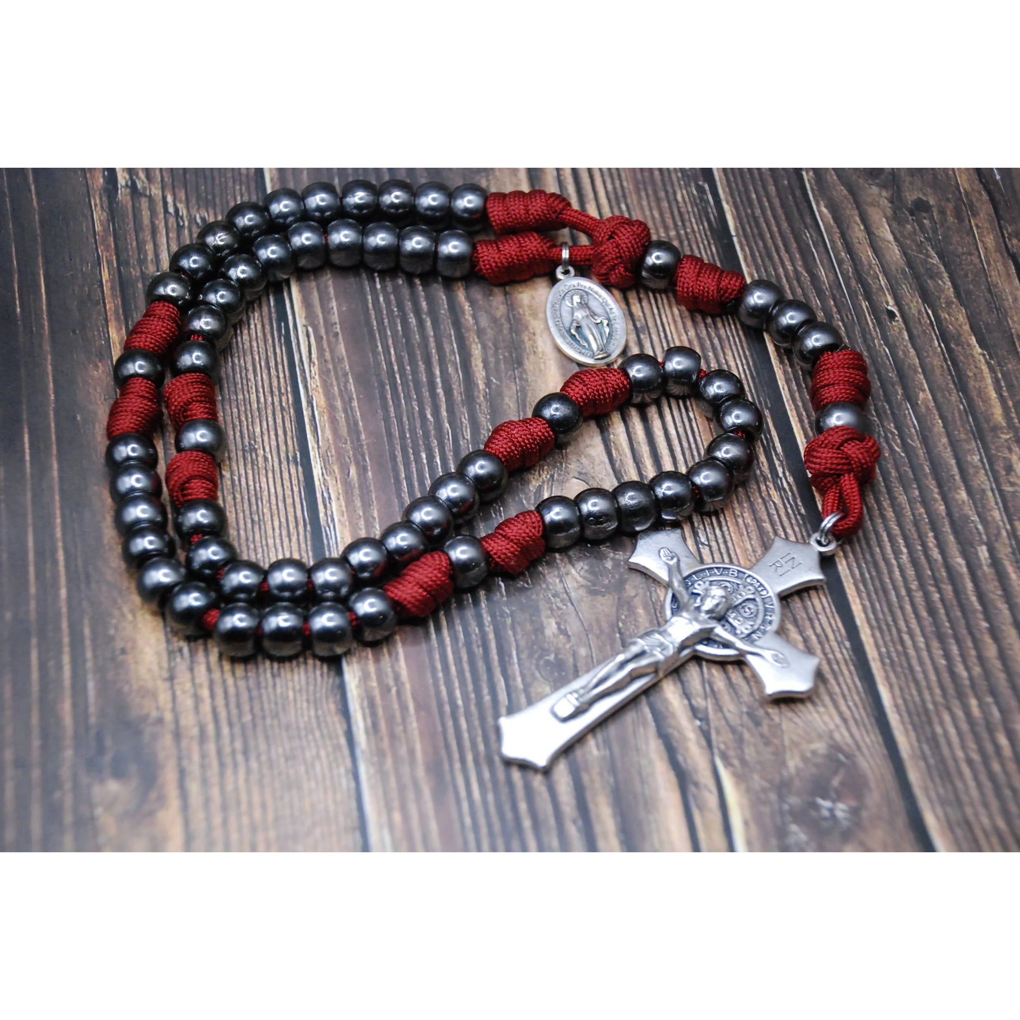 Rosary beads: dark gray, with red cord; crucifix and medal are silver-toned metal.