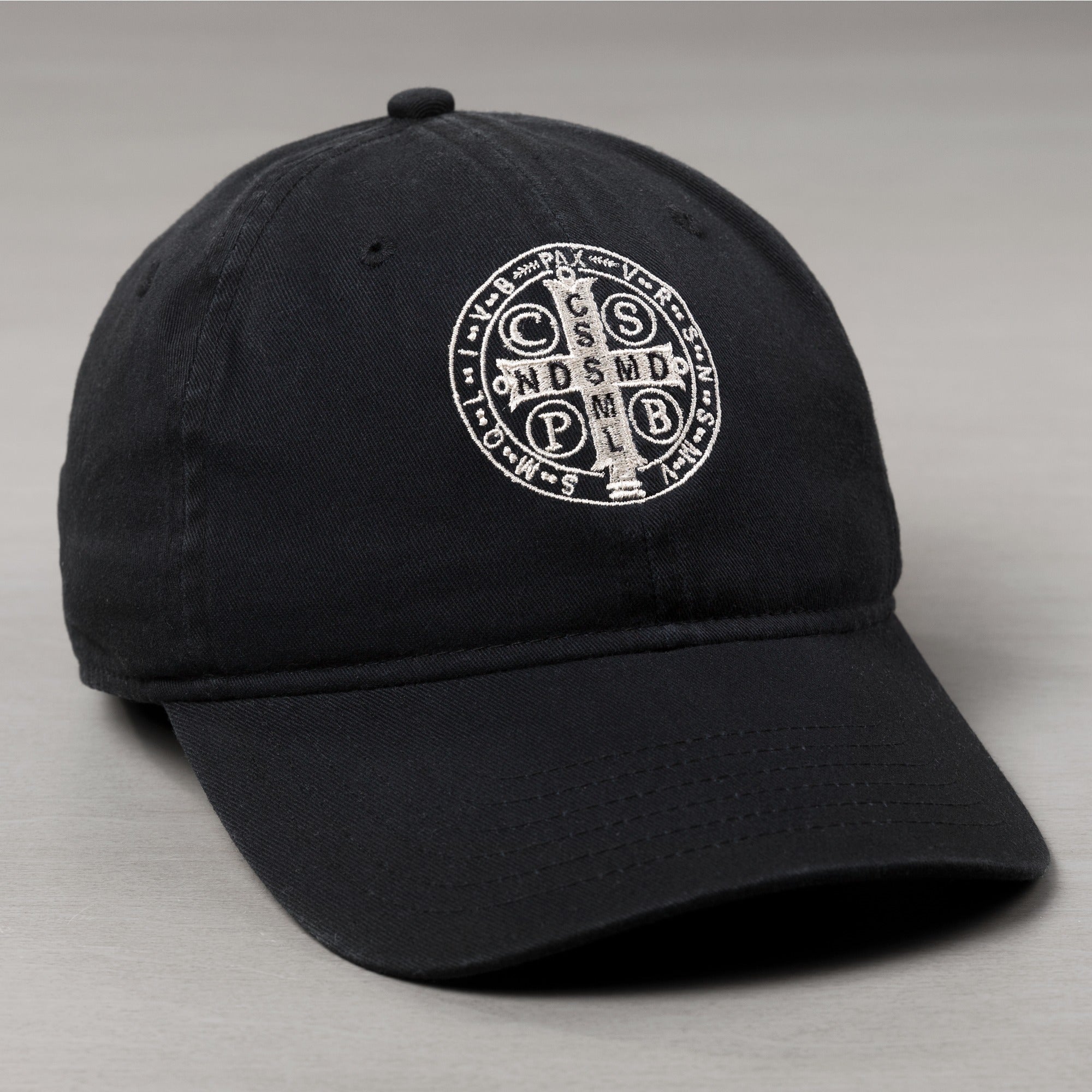 Black cotton cap with embroidered St. Benedict medal on the front panel.