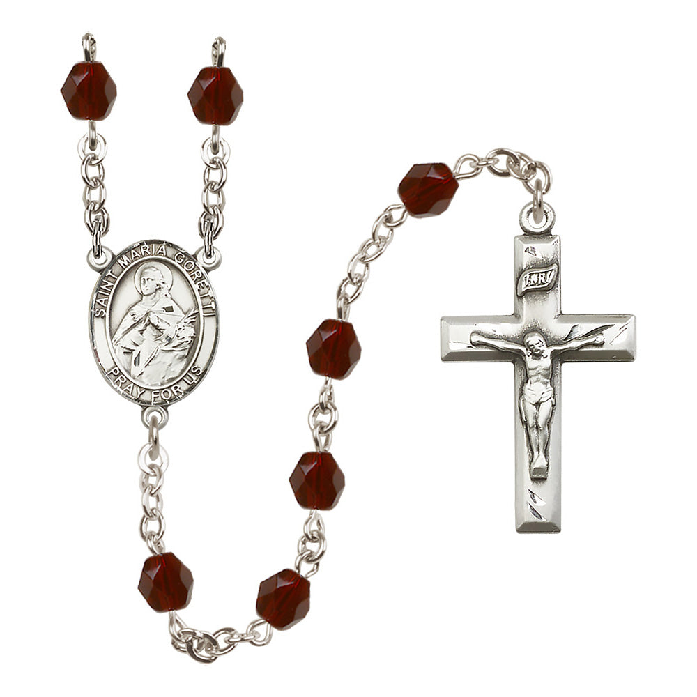 Religious rosary with silver chain, red faceted beads, crucifix, and Saint Maria Goretti medallion.