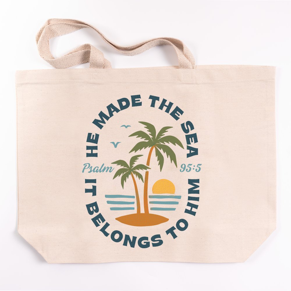 Canvas tote bag with handles, "He Made The Sea, It Belongs To Him" text and palm tree graphic, off-white.