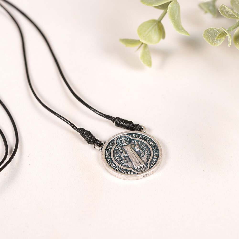 Saint Benedict medal necklace with black cord and silver and blue medallion pendant.