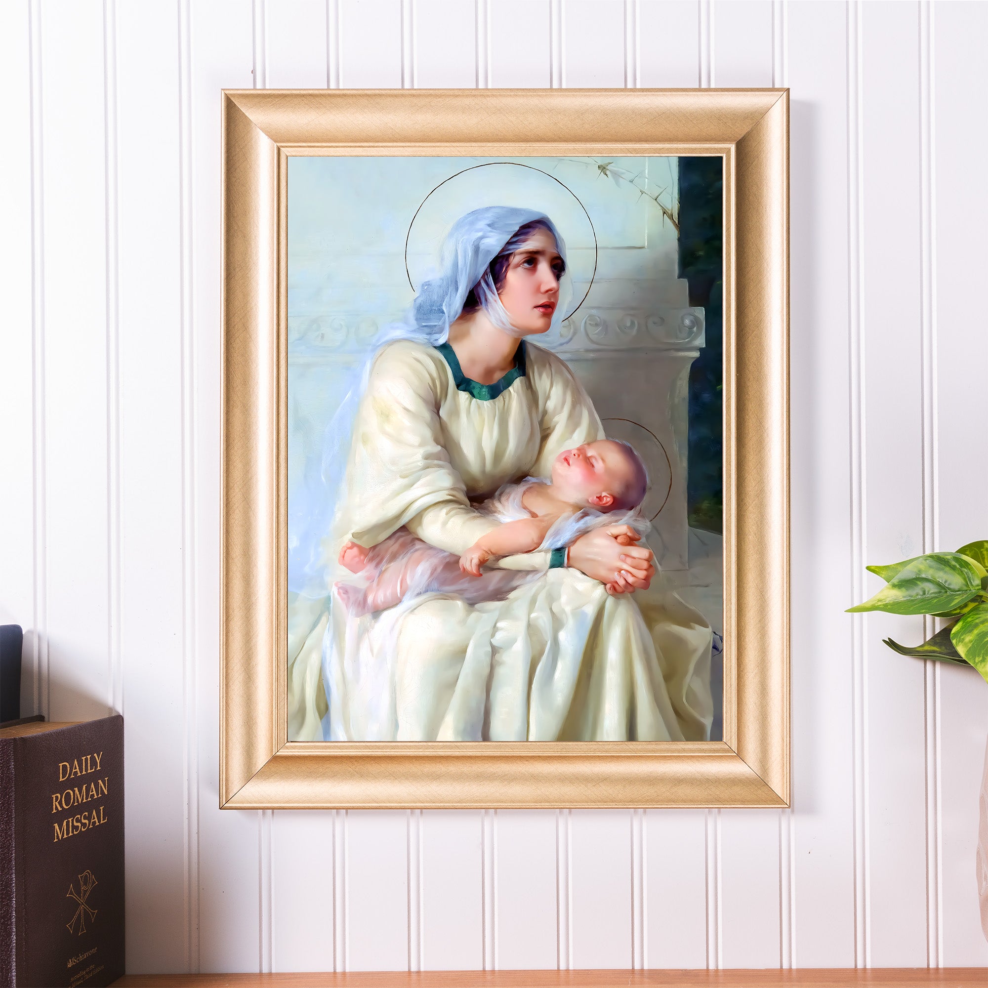 Framed painting of Mary holding baby Jesus in cream and blue tones, gold frame, traditional style.