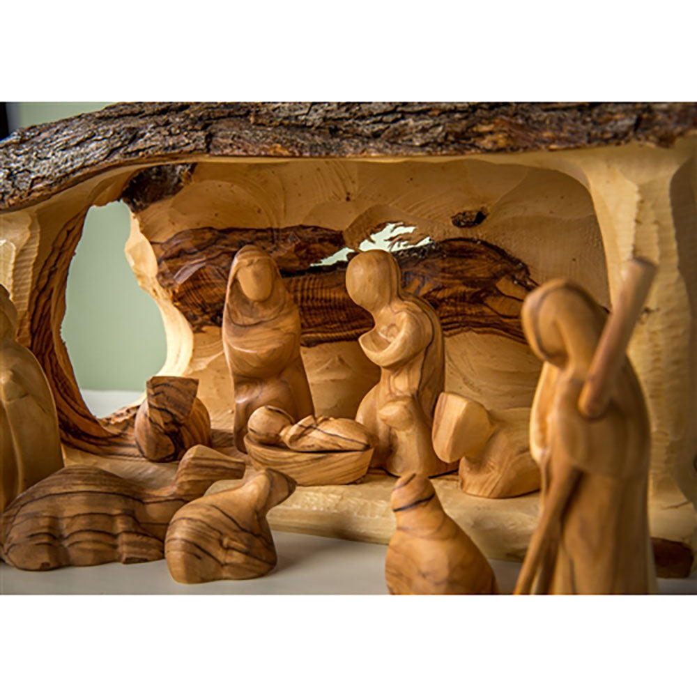 Hand-carved olive wood Nativity scene features Mary, Joseph, baby Jesus, and animals inside a bark-covered stable.