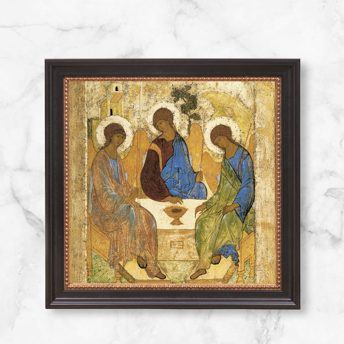 Framed Orthodox icon of the Holy Trinity, featuring three angels, painted in gold and brown hues with blue and green robes.