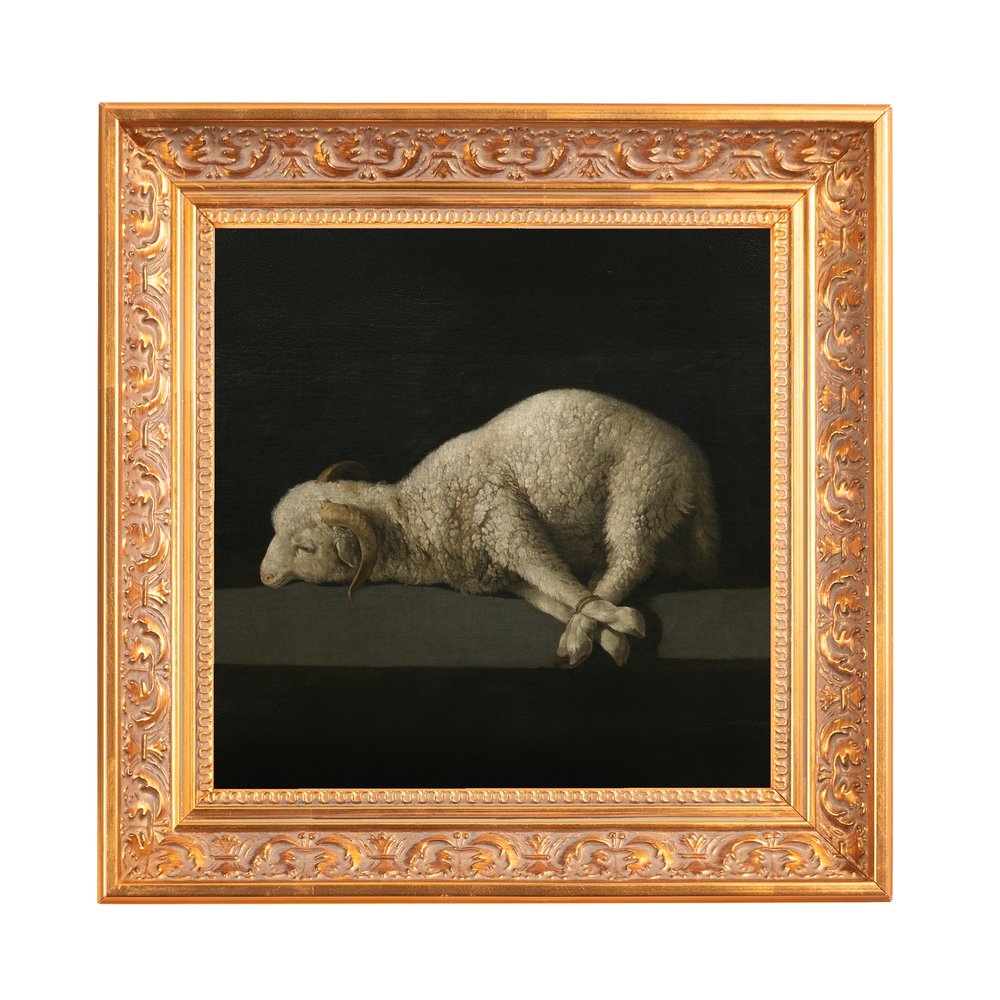 Framed oil painting depicting a lamb lying down with bound legs, in dark tones, with an ornate gold frame.
