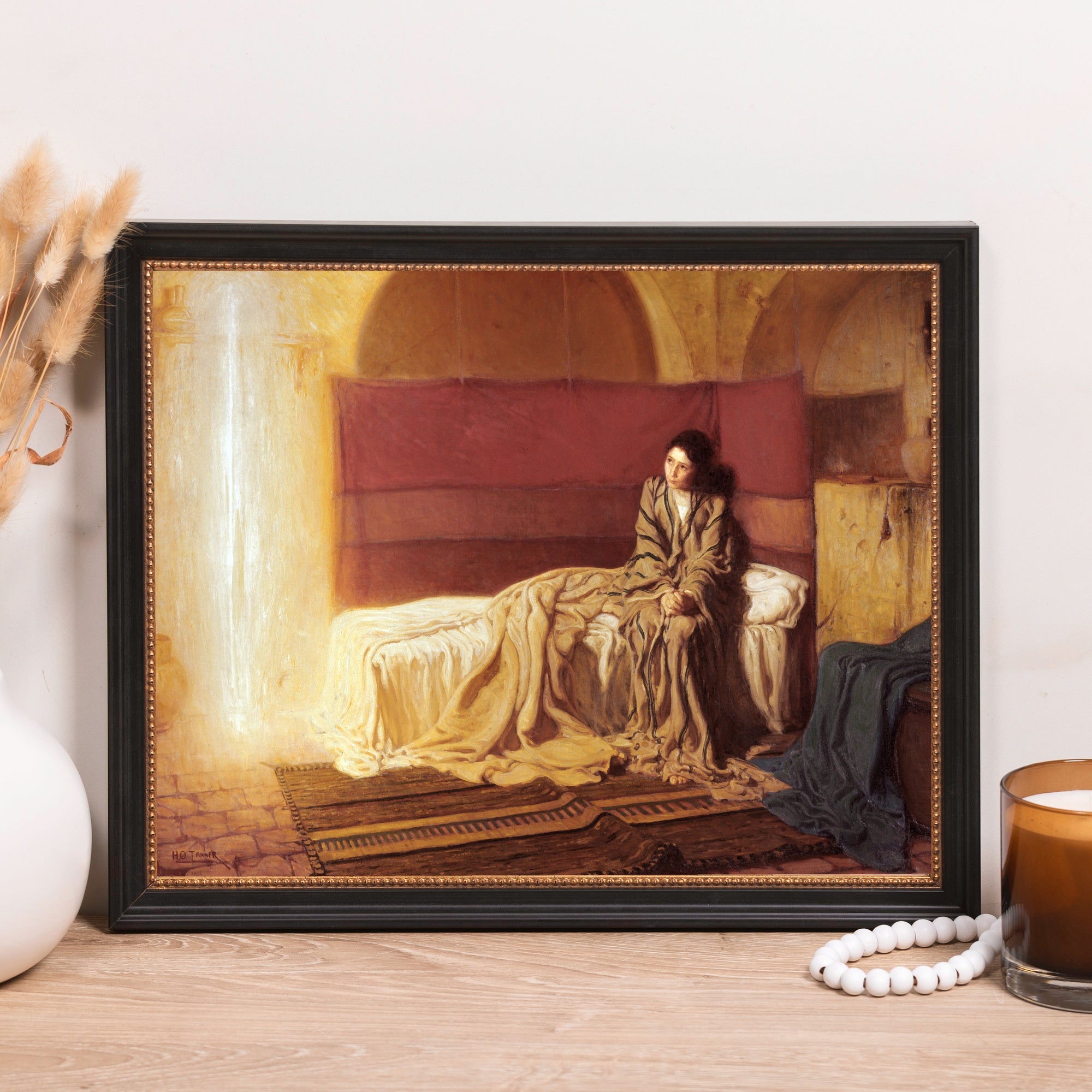 Framed oil painting print depicting a woman on a bed with red and gold fabric in a black frame.