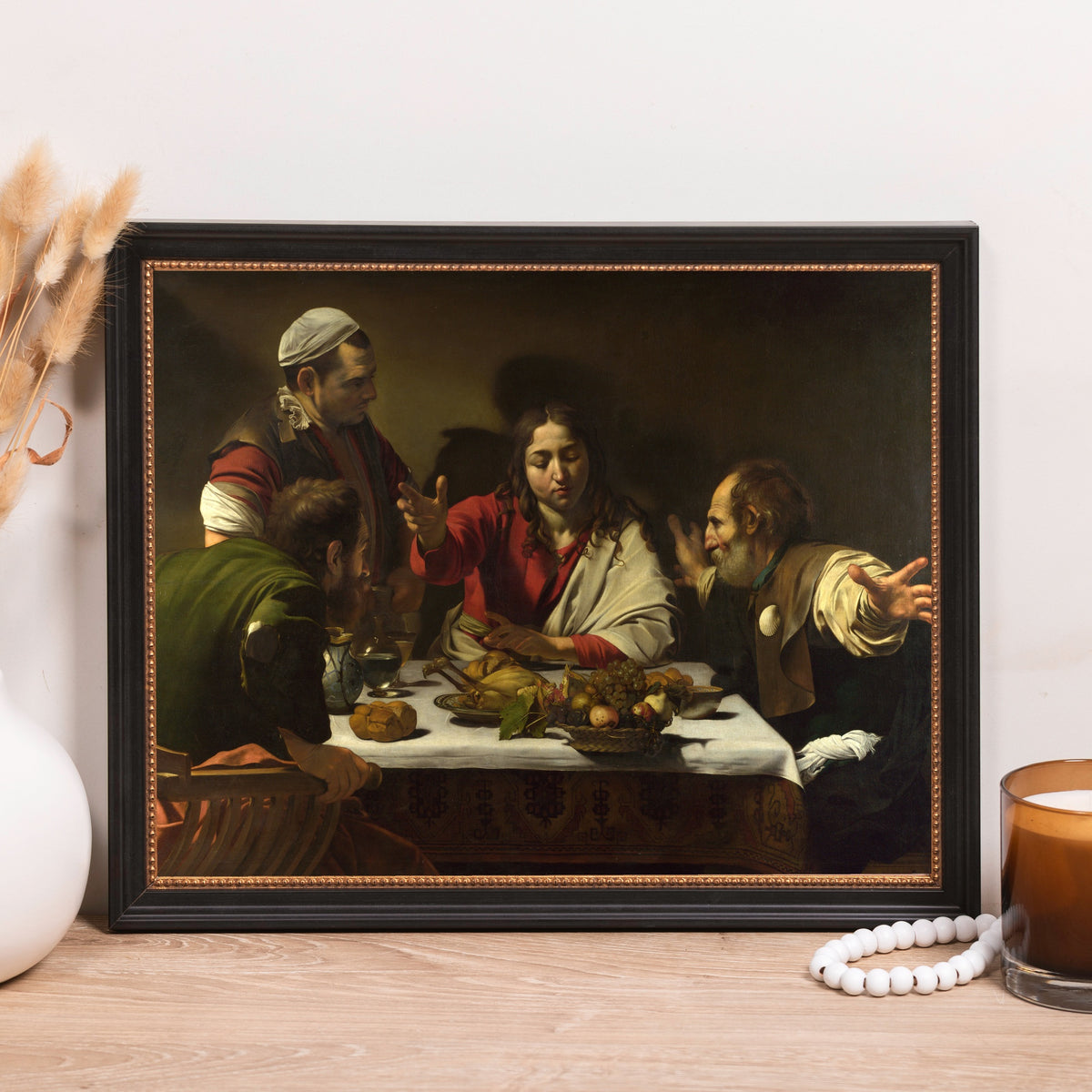 Framed print of Caravaggio's "Supper at Emmaus" painting with dark colors and black frame.