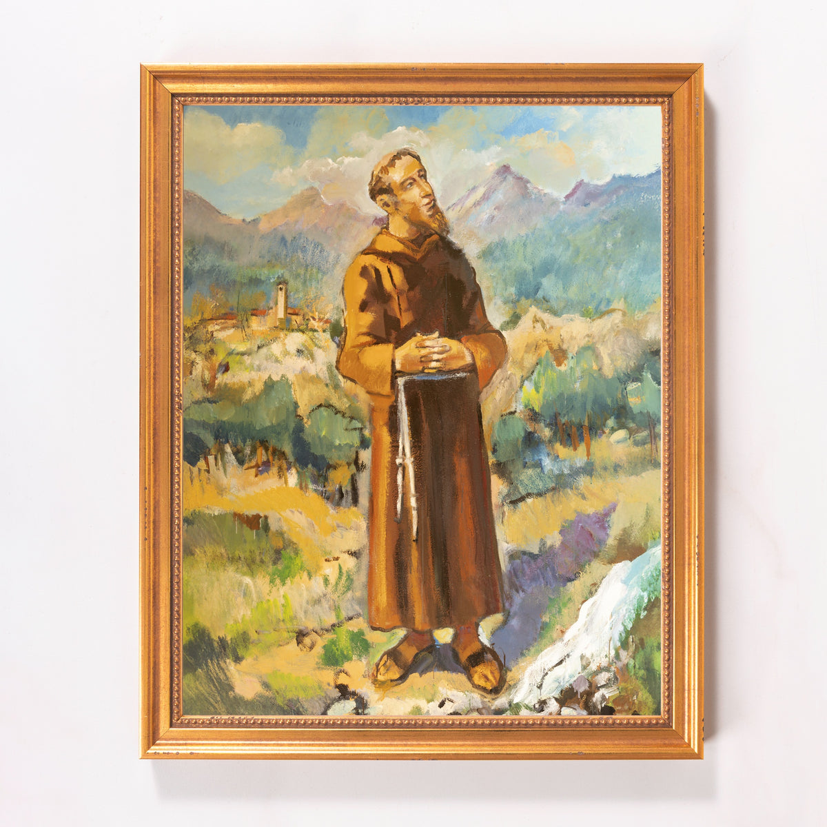 Framed oil painting of a monk in a brown robe with a rosary in a mountain landscape.