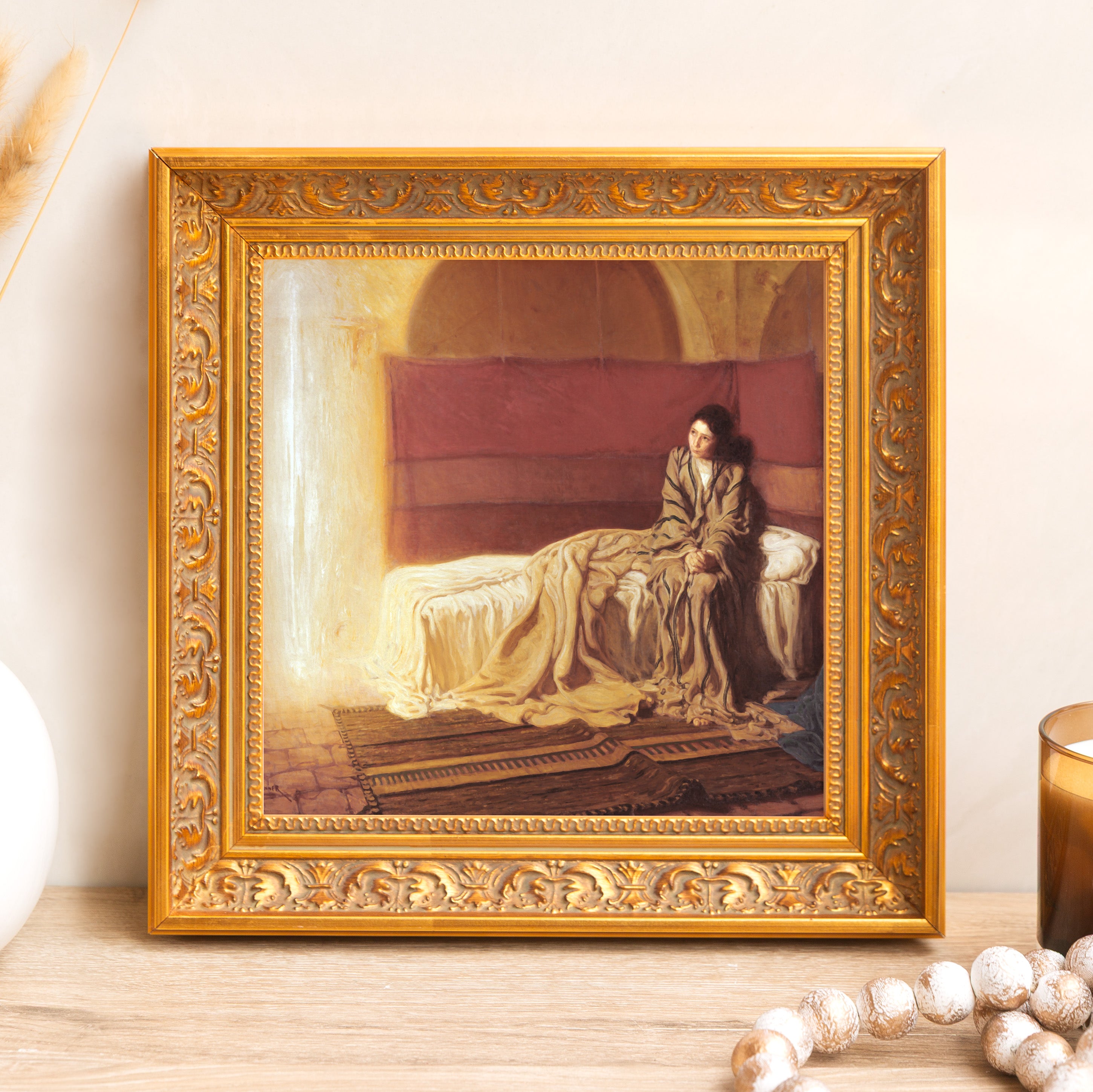 Framed print of a woman sitting on a bed with gold ornate frame, for wall decor.