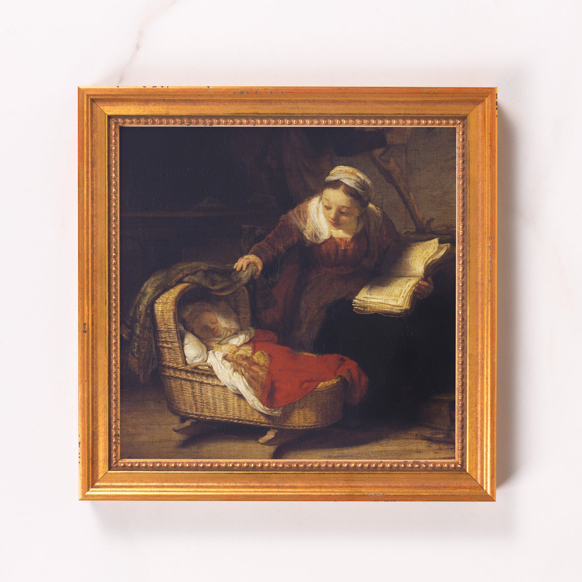 Framed oil painting of a woman with a book watching over a baby in a wicker crib.