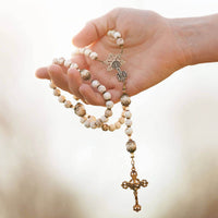 Hand holding a rosary with a blurred background
