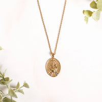 Gold Sacred Heart pendant necklace on a light background.