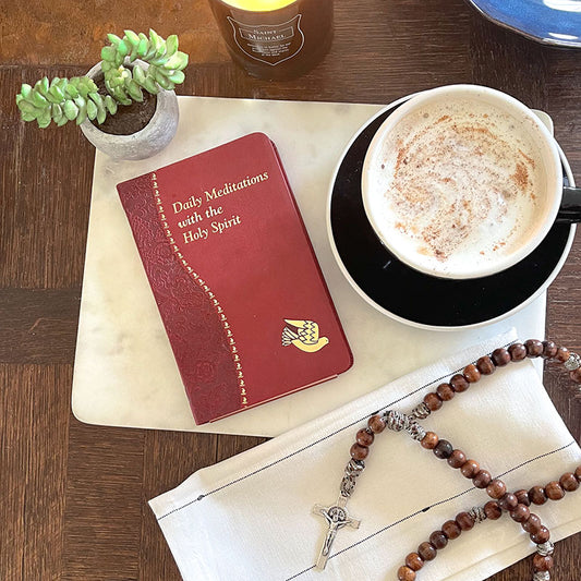 Daily Meditations with the Holy Spirit book on a table with a fancy coffee, a succulent, and a wooden rosary.