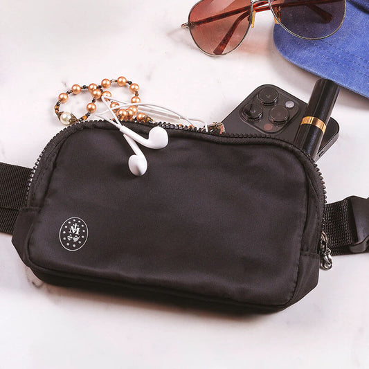 Black travel pouch with a small white Sacred Heart logo with white headphones and other items coming out.