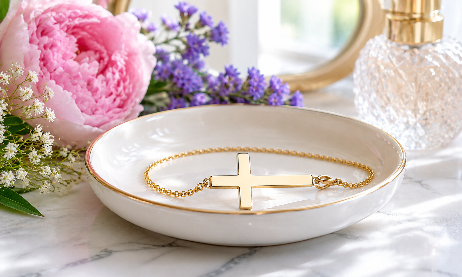 A sideways cross bracelet sitting in a lovely trinket dish on a vanity table