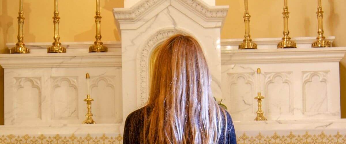 Woman standing and facing a church altar with candles