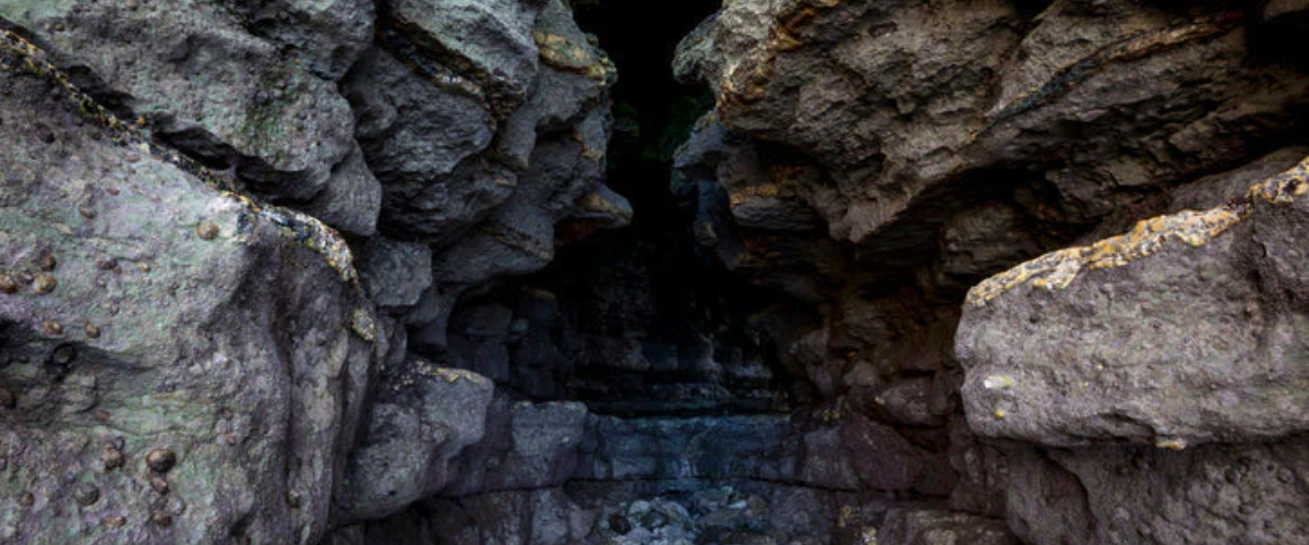 Rocky cave passage with rugged stone walls and scattered rocks