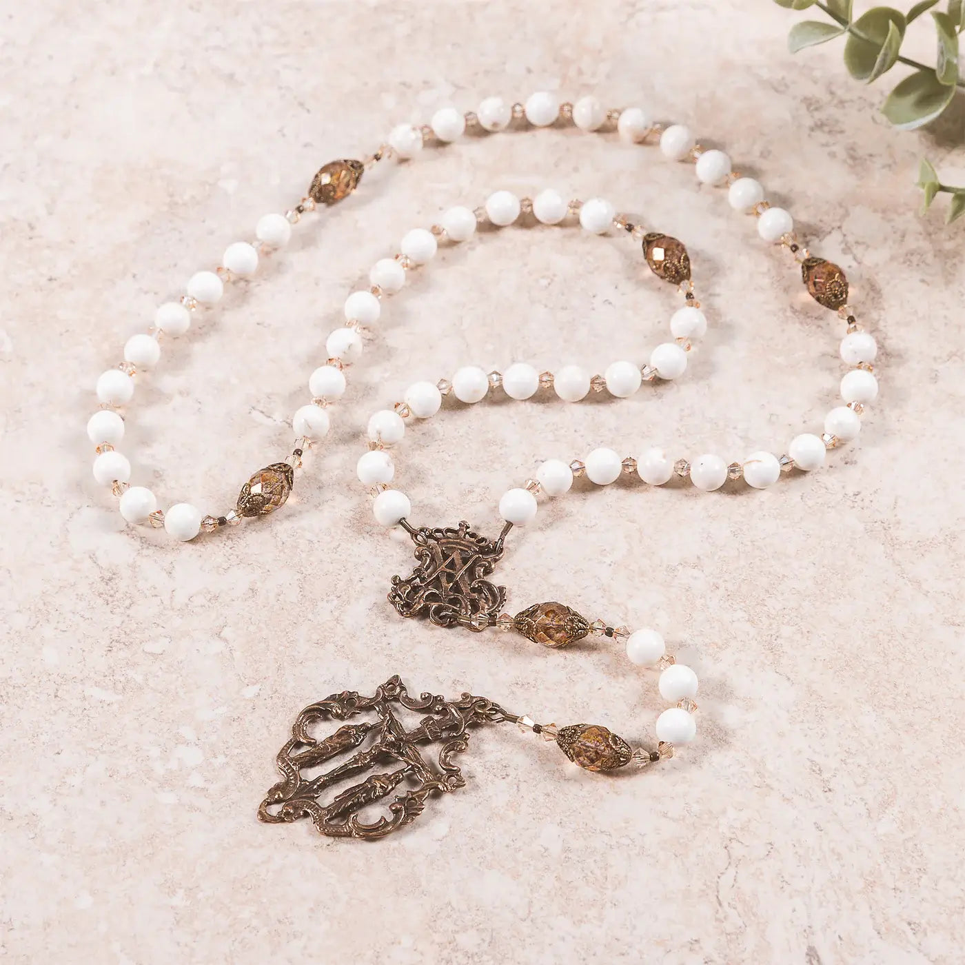 White ornate rosary featuring intricate Marian design on a white background.