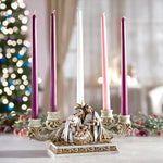 Decorative candle holder with nativity scene in front of a Christmas tree.