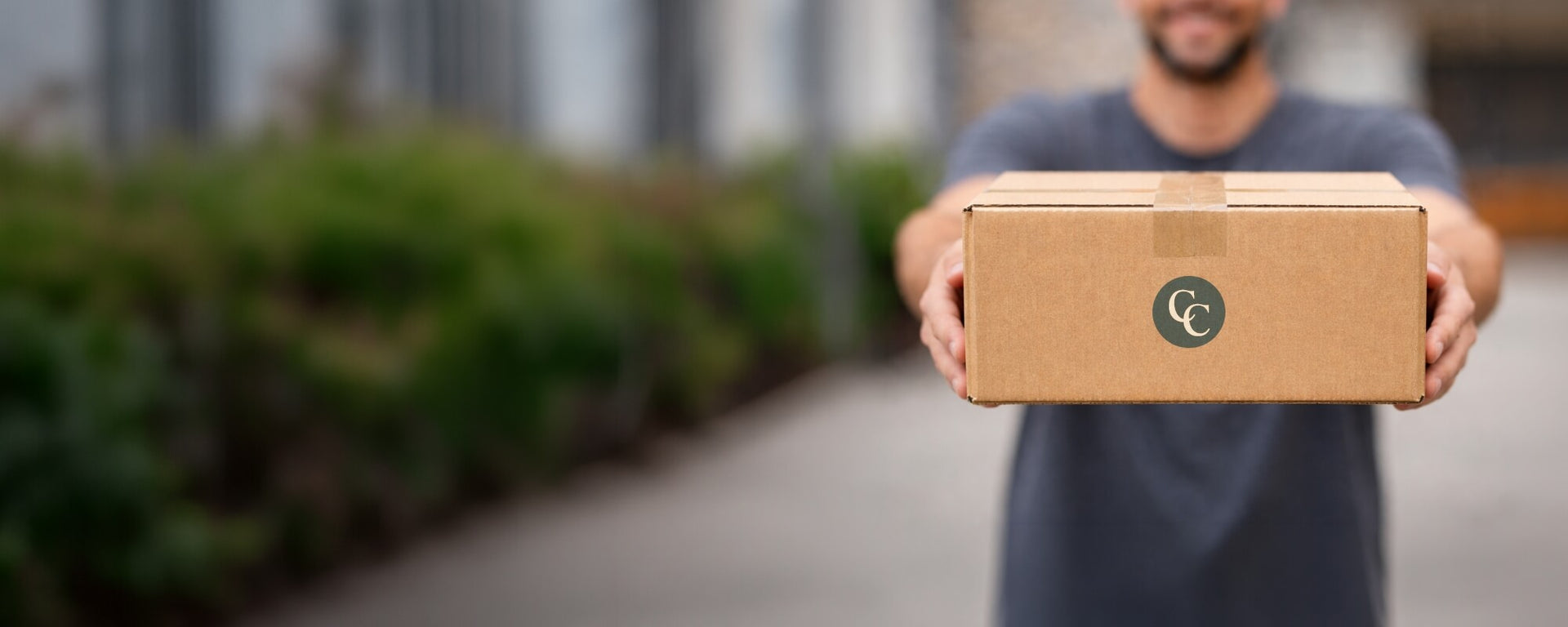 Man holding a cardboard shipping box with logo, representing home delivery and free shipping