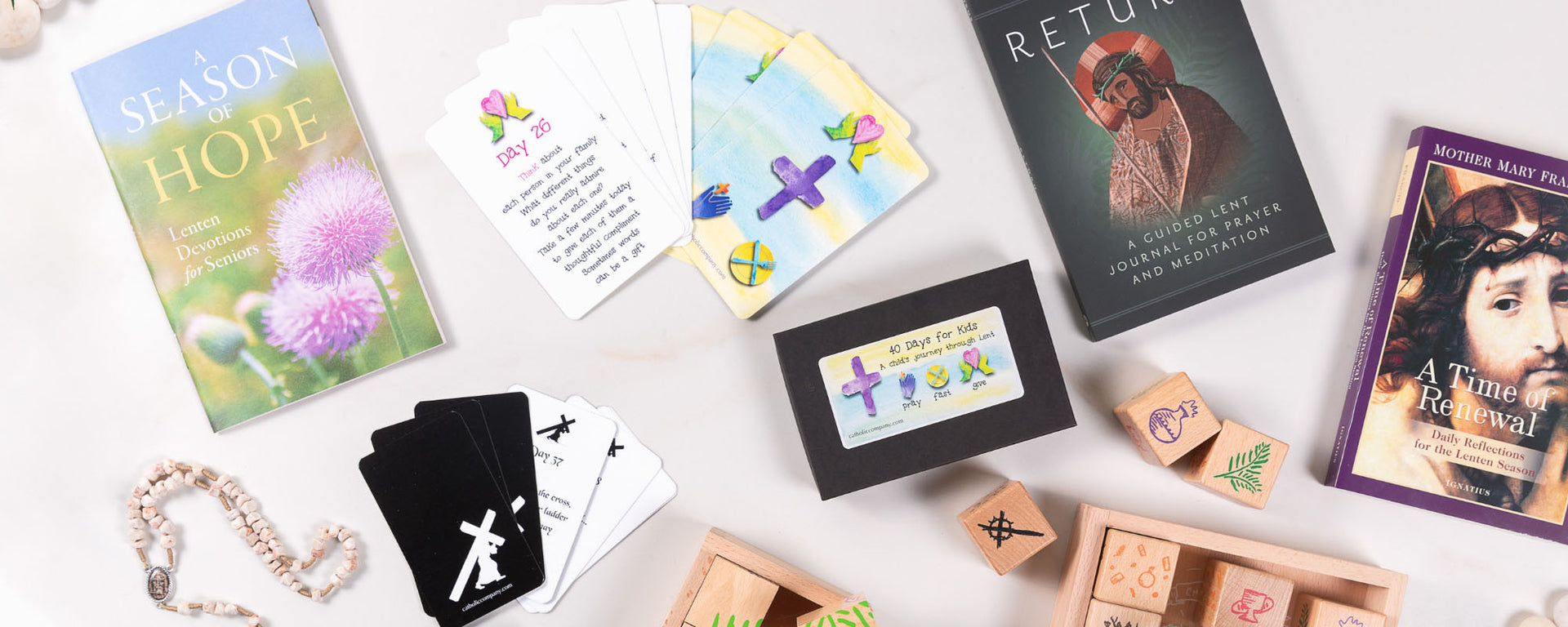 Flat lay of Lent-themed devotional books, prayer cards, wooden religious blocks, and rosaries arranged on a white background.