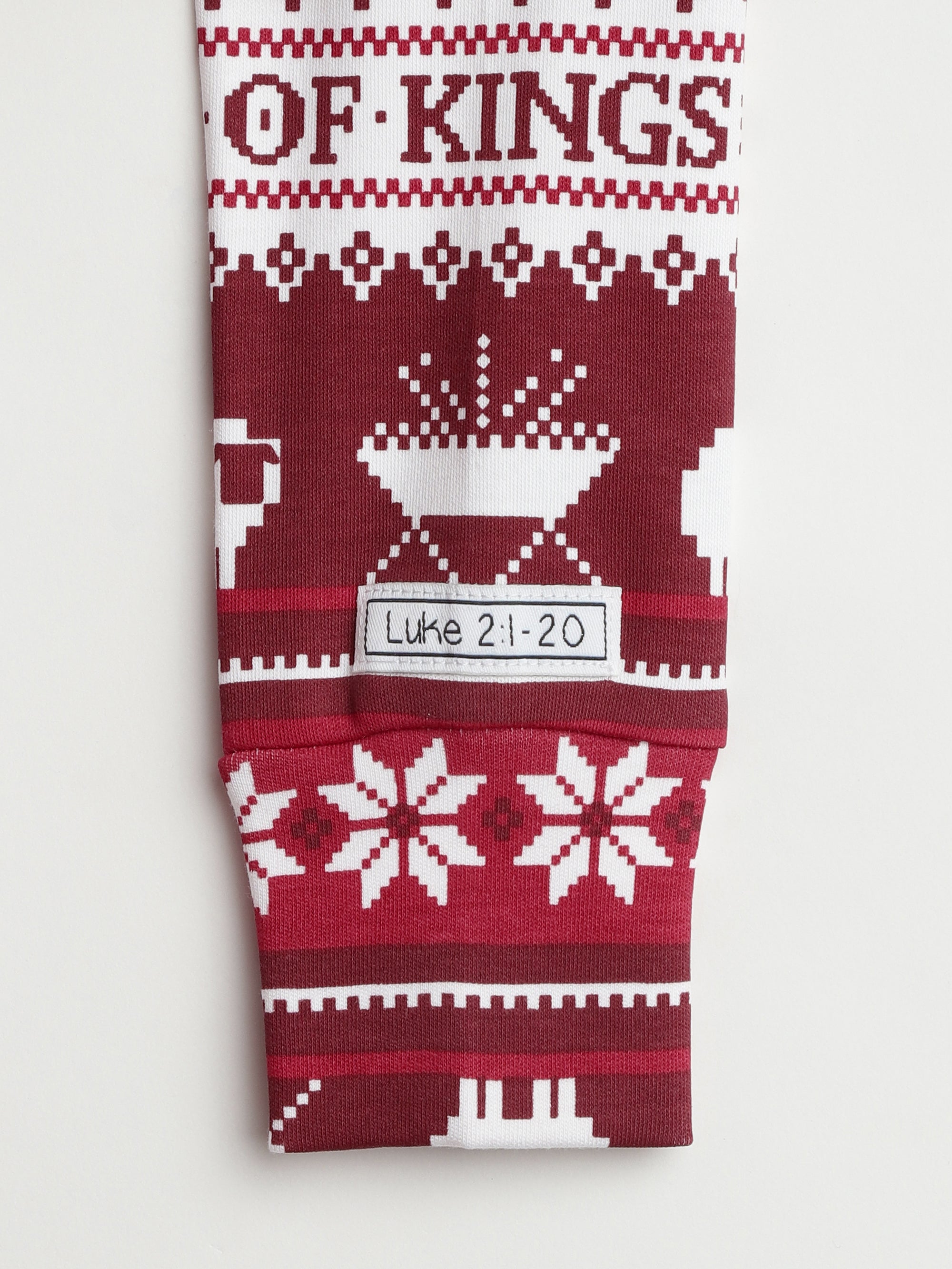 Christmas pajamas with "of kings" text, burgundy and white fair isle pattern with manger and Luke 2:1-20 quote on cotton blend.