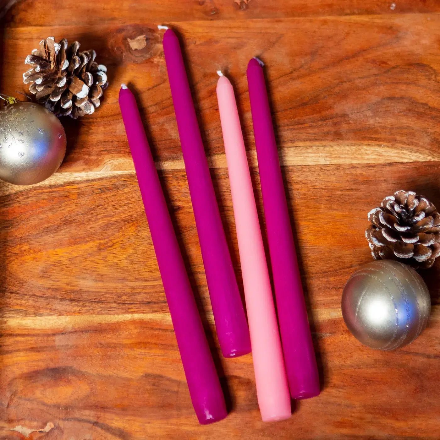 Advent candles laid out ona wood table with festive decor.