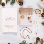 Jewelry, stationairy items, and other Catholic gifts on white backdrop with decorative Christmas elements